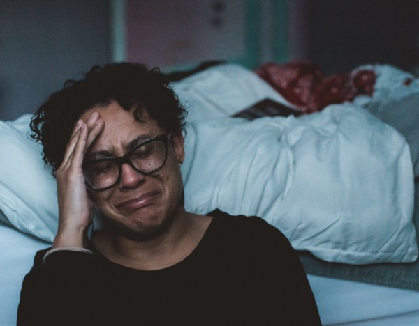 A woman sitting at bedside crying